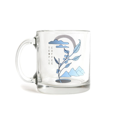 Glass mug with blue and black coffee plant, mountains, and clouds design. 