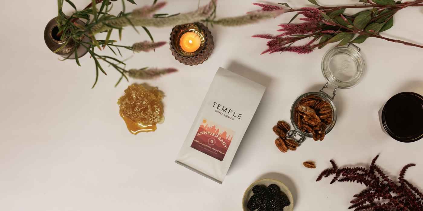 Bag of Anniversary Blend coffee surrounded by pecans, blackberries, and honeycomb. 
