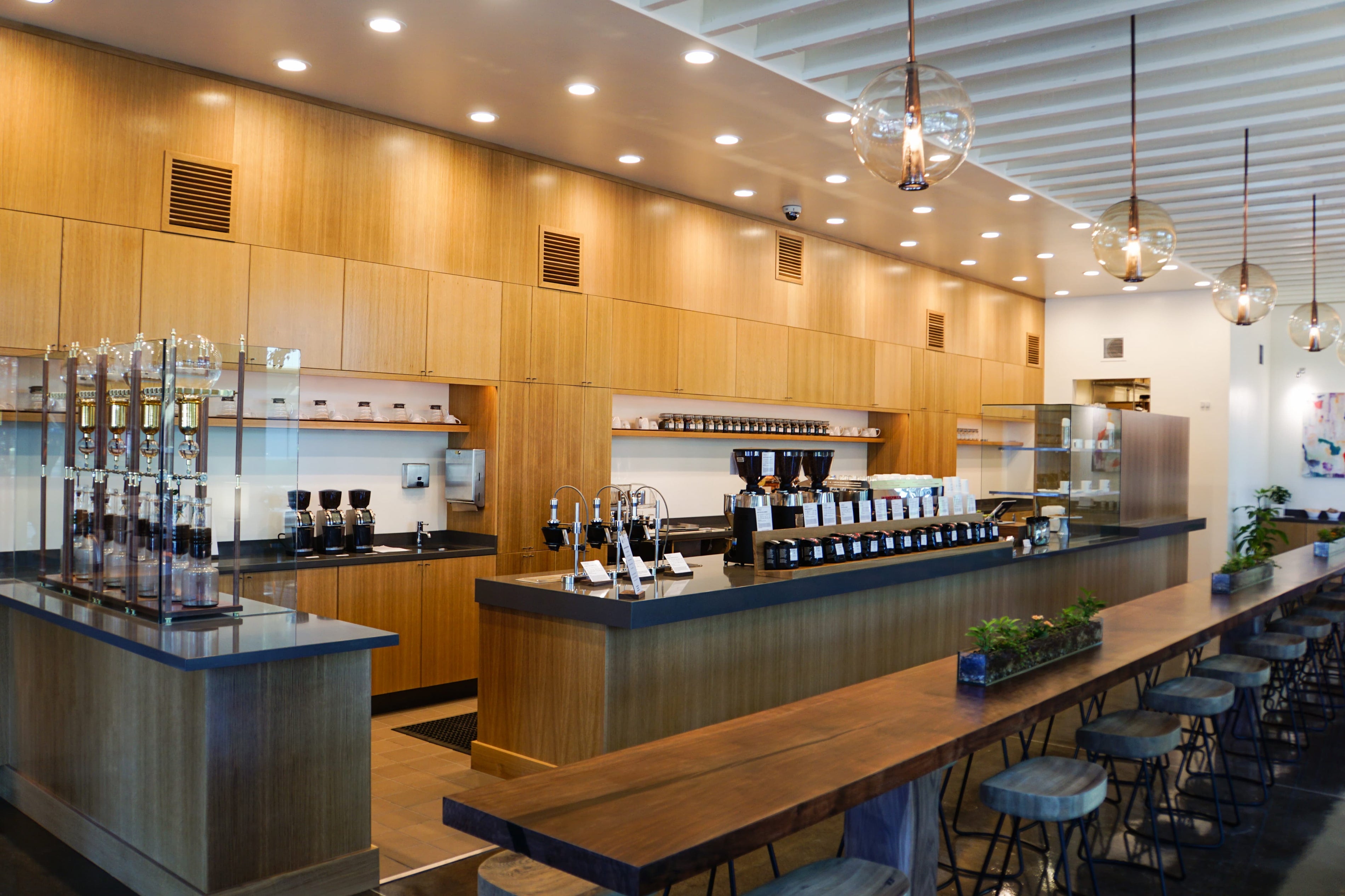 Modern coffee shop interior with wooden cabinets, bar, and stools.