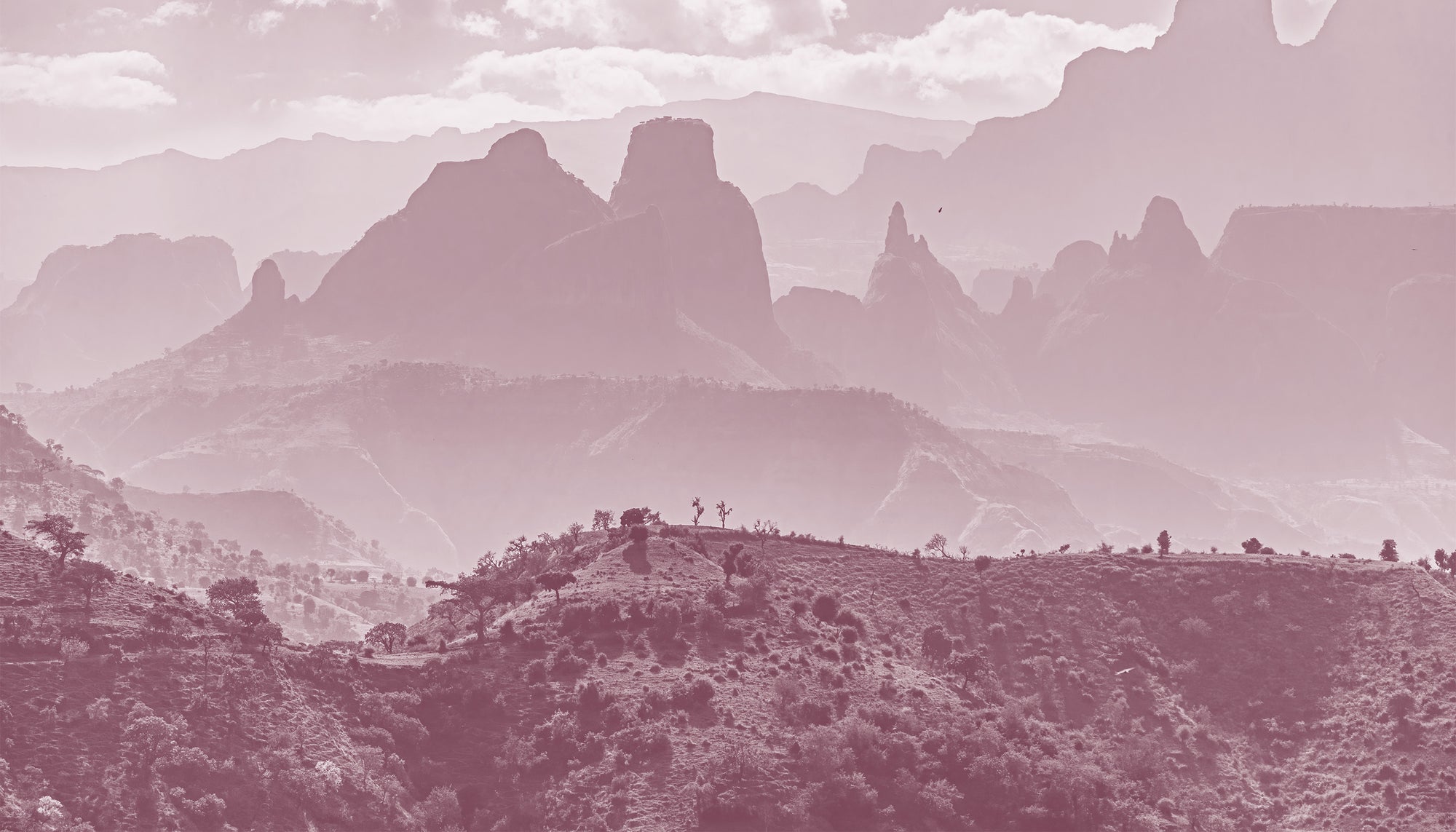 Mountain landscape with rugged peaks and a hazy sky.