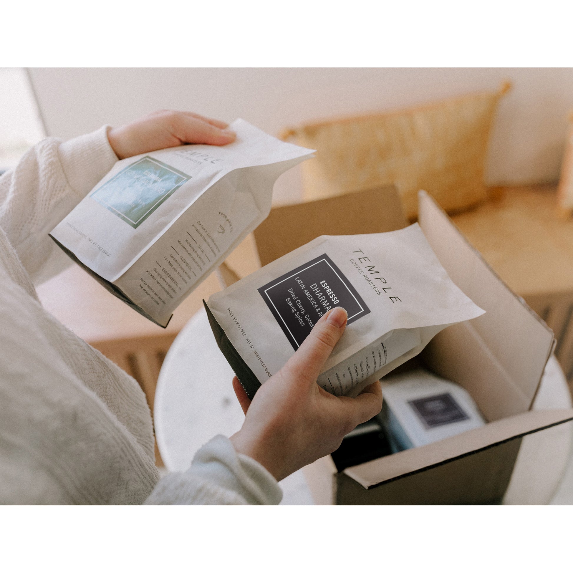 Person unpacking boxes with 'Temple' branding in a home setting.