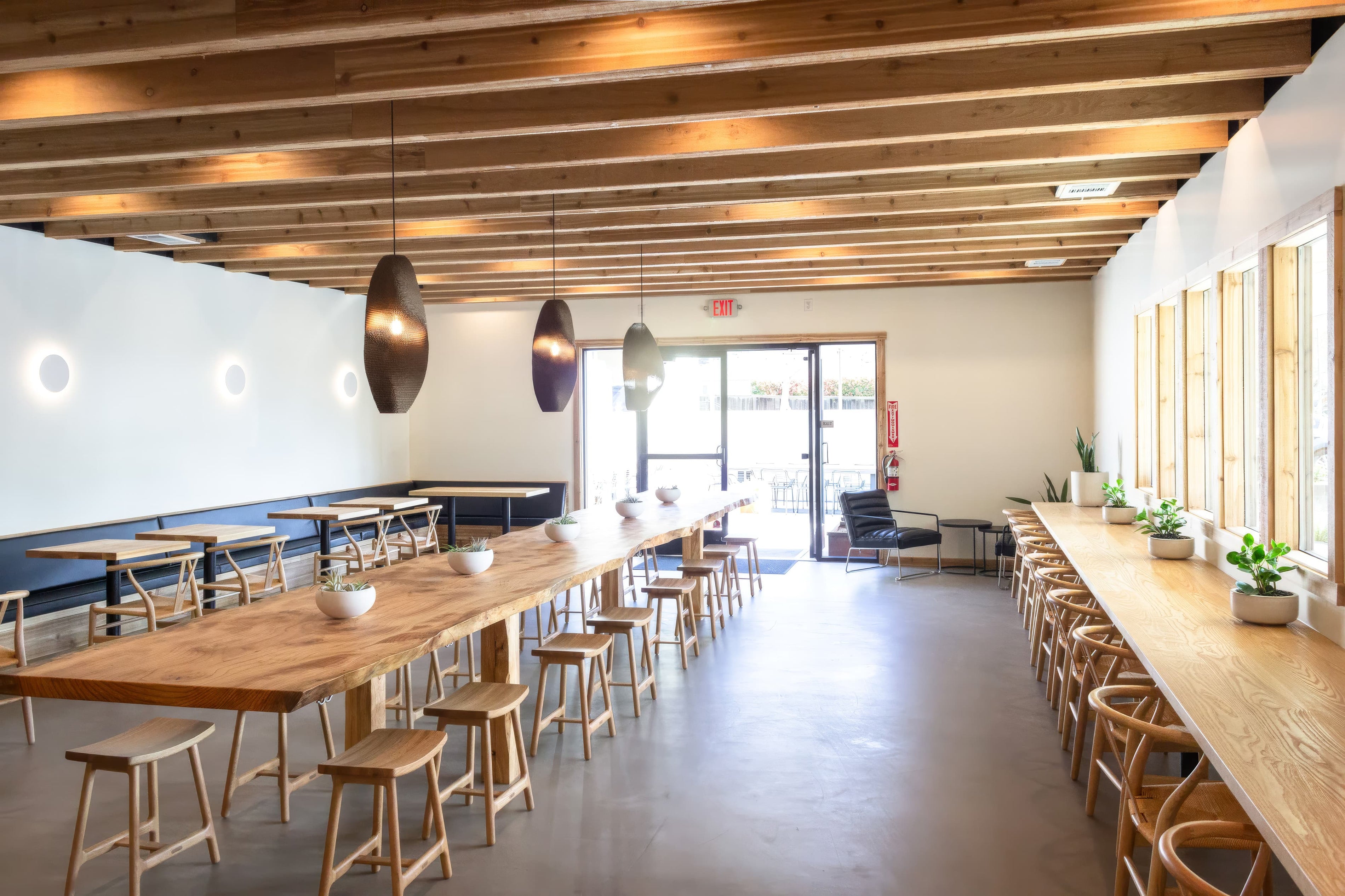 Modern interior with long wooden tables and chairs in a well-lit room.
