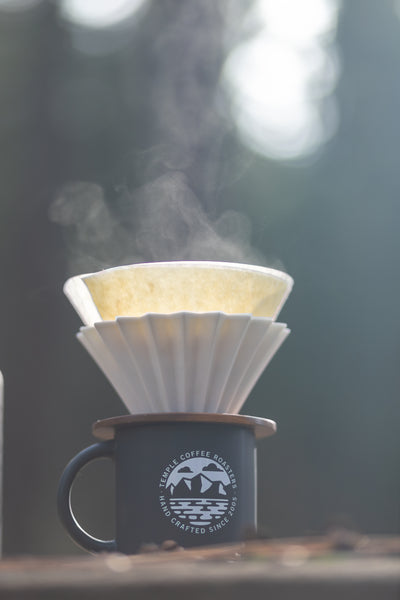 Coffee filter with steam over a mug on a blurred natural background