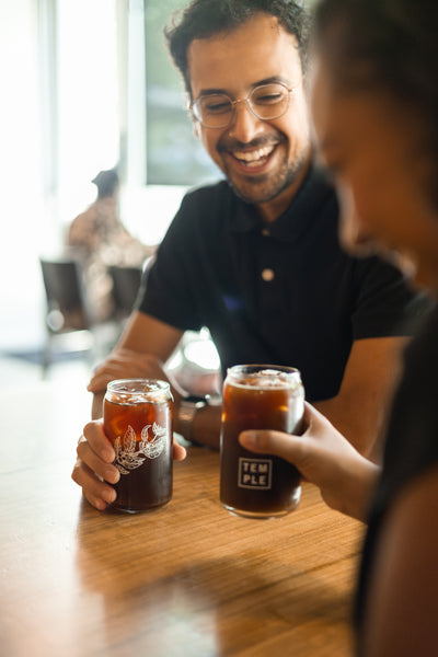 Two people holding glass cans filled with cold brew coffee.