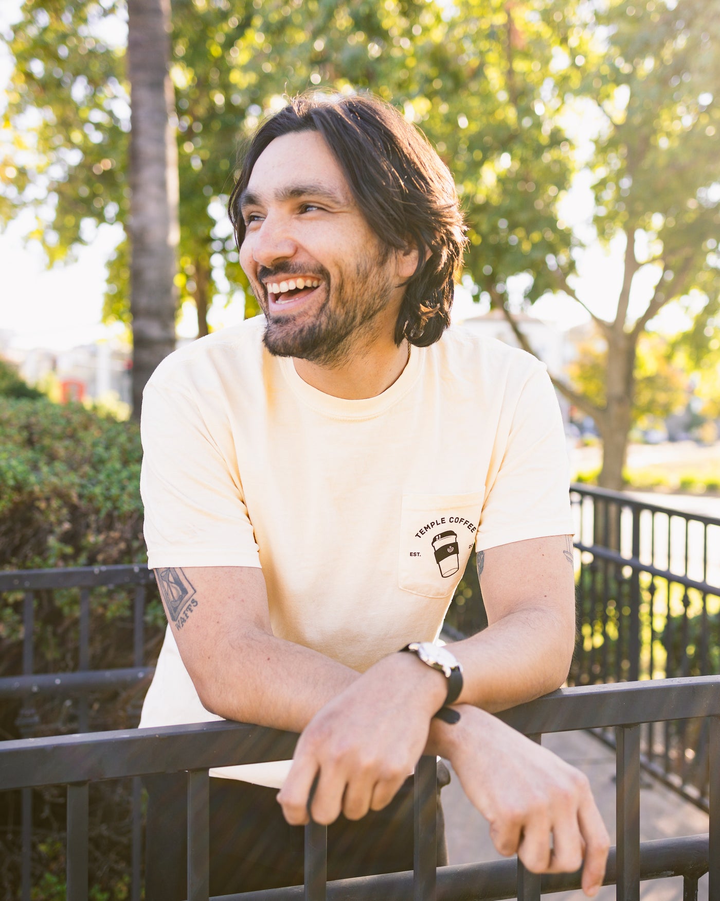 Person wearing a cream-colored T-shirt with a to-go cup graphic and text on the front pocket.