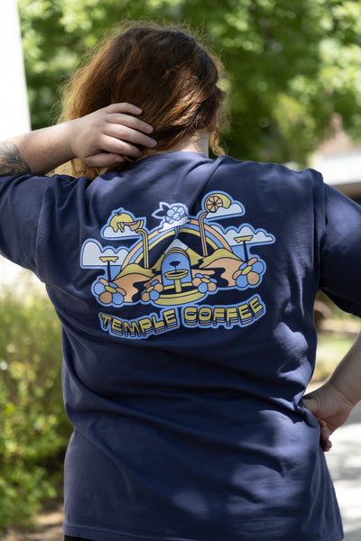 Person wearing a navy blue t-shirt with 'Temple Coffee' logo on the back, standing outdoors.